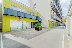 A building with a yellow facade, a blue awning, and a black spiral staircase.
