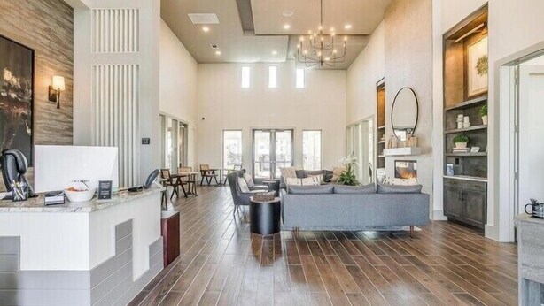 A spacious hotel lobby with a reception desk, seating area, and a large window providing natural light.