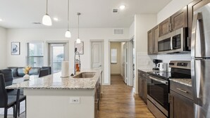 A modern kitchen with granite countertops, stainless steel appliances, and a central island.