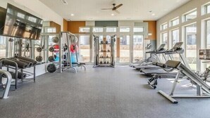 Une salle de sport équipée de tapis de course, d’appareils de musculation et d’un miroir.