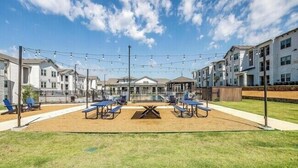 A courtyard with outdoor seating, a central table, and string lights. - Chisholm Trace 827 I Comfy 2 Bed 2 Bath (Cleburne)
