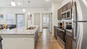 A modern kitchen with granite countertops, stainless steel appliances, and a central island. - Chisholm Trace 827 I Comfy 2 Bed 2 Bath (Cleburne)