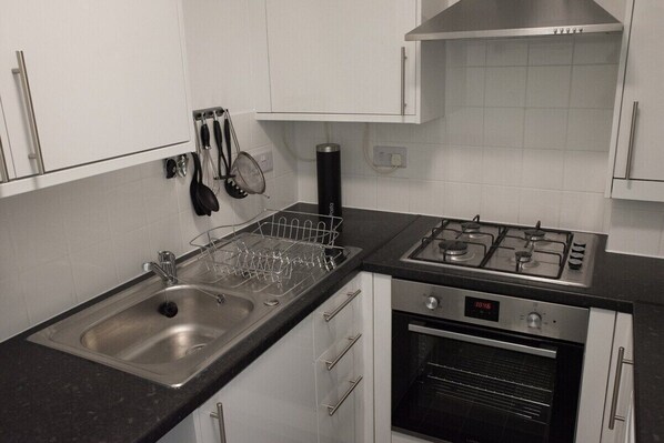A kitchen with a stainless steel sink, a gas stove, and a built-in oven. - Beautiful, annex, 10min from Cambridge centre (Great Shelford)