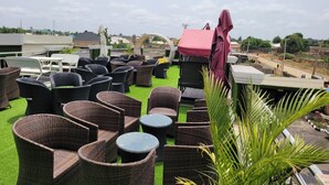 A rooftop terrace with wicker furniture and a green artificial turf. - TOZY  HOTEL (Gwagwalada)