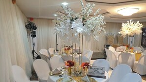 A banquet hall with round tables, white chairs, and floral centerpieces. - TOZY  HOTEL (Gwagwalada)