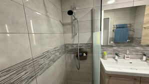 A bathroom with a shower, a sink, and a mirror.