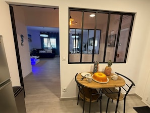 A dining area with a wooden table, chairs, a cake, and a pineapple. - Apartment in the center of ROSES (Roses)