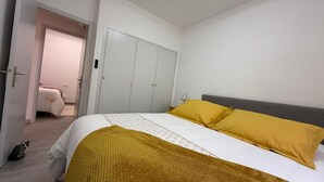 A bedroom with a bed, a wardrobe, and a door leading to another room.