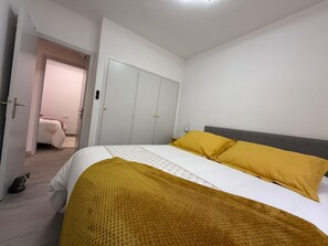 A bedroom with a bed, a wardrobe, and a door leading to another room. - Apartment in the center of ROSES (Roses)