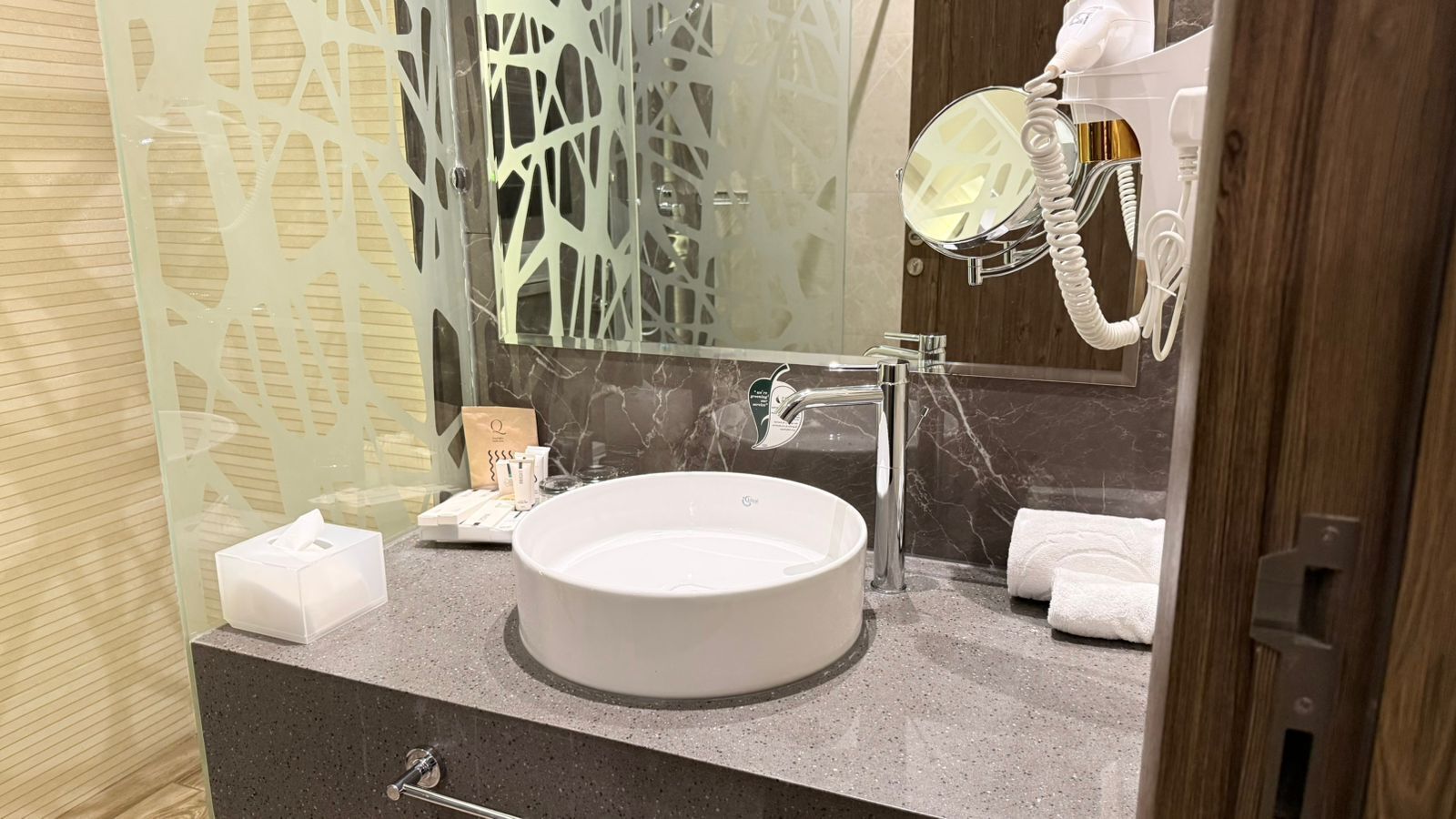 Un bagno con un lavandino bianco rotondo, uno specchio e un porta asciugamani.