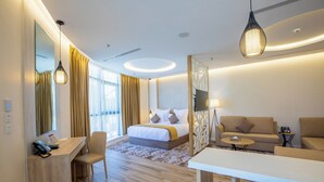 A modern hotel room with a bed, a desk, a sofa, and a dining area. - Le Reve Hotel (Taif)