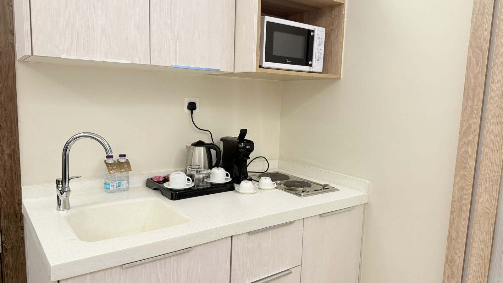 Eine Küchenzeile mit Mikrowelle, Kaffeemaschine und Spüle, komplett mit Wasserflaschen und Bechern.