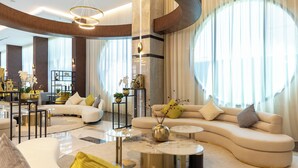 A spacious living area with a curved sofa, round coffee tables, and a dining area with a modern chandelier. - Le Reve Hotel (Taif)