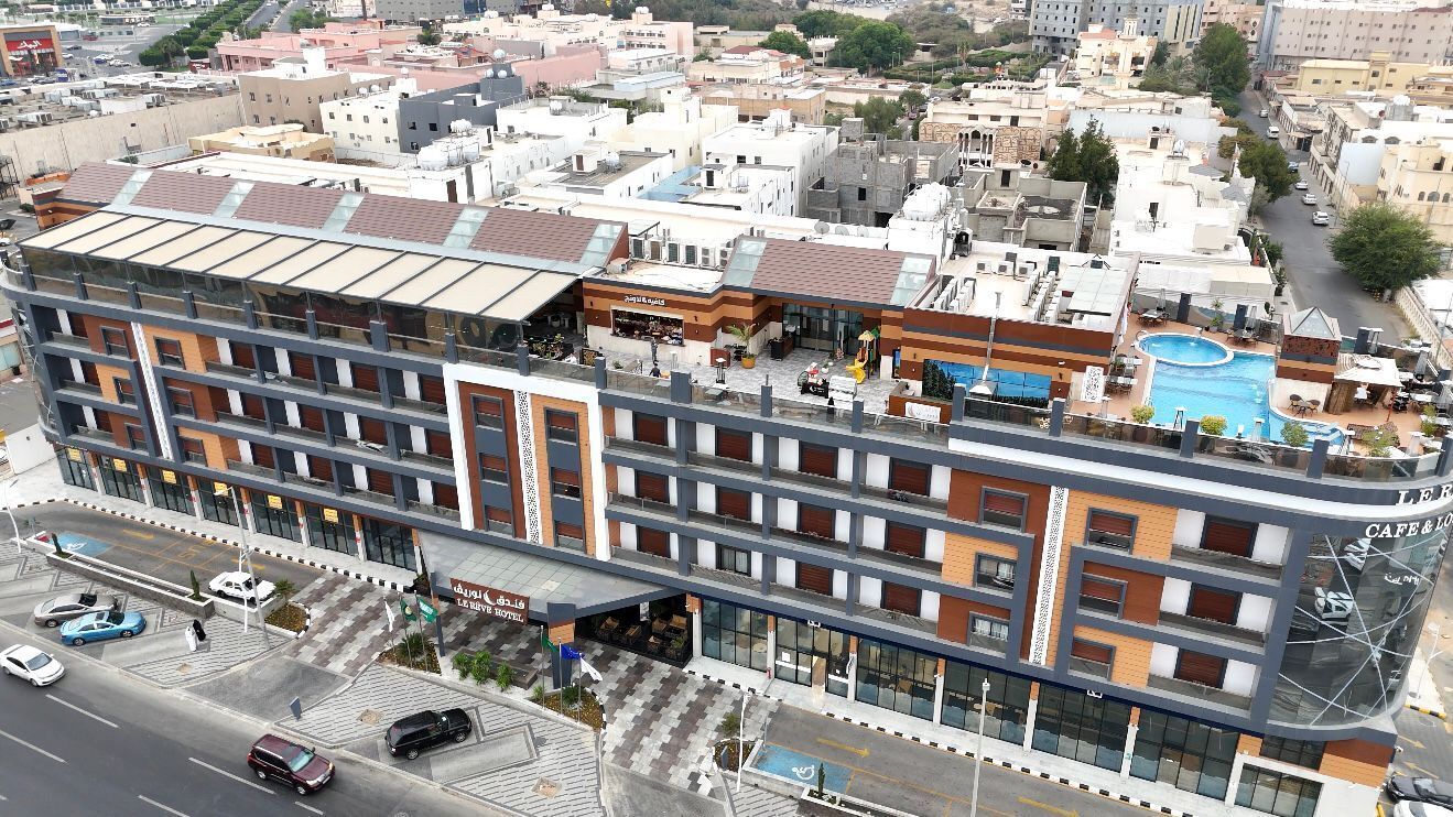 A multi-story hotel with a rooftop pool, a cafe, and a parking area.