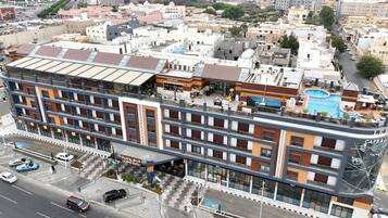 A multi-story hotel with a rooftop pool, a cafe, and a parking area.