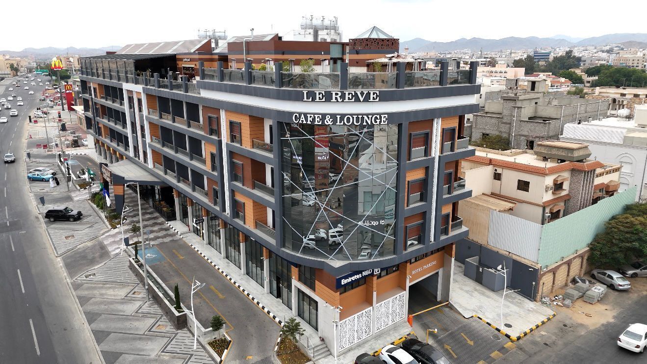 A multi-story building with a cafe and lounge on the ground floor, featuring a modern architectural design with glass and metal elements.