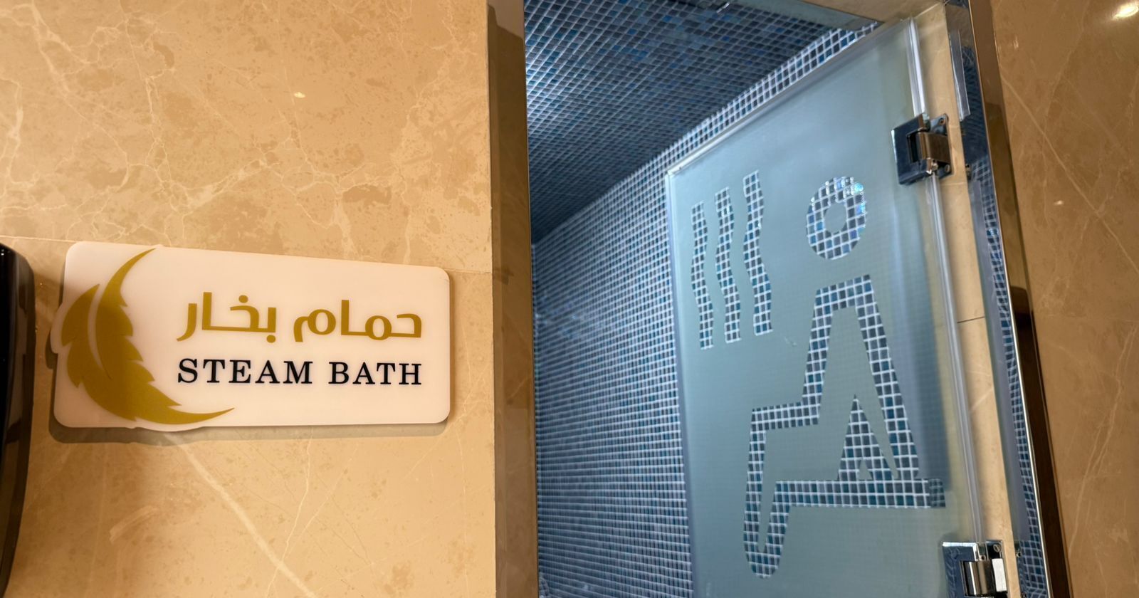 Un letrero para un baño de vapor con texto en árabe y traducción al inglés.