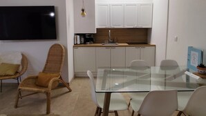 A compact kitchen with white cabinets, a built-in microwave, and a coffee maker. There is a glass dining table with four chairs. - La grange aux fées Amnéville (Amnéville)