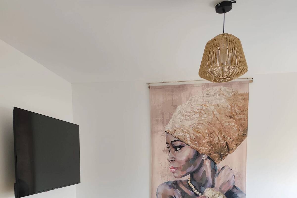 Ein Schlafzimmer mit einem Bett, einem an der Wand befestigten Fernseher, einem Holzschrank und einem Gemälde.