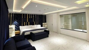Une chambre moderne dotée d’un grand lit, d’un coin salon et d’une douche à parois de verre.