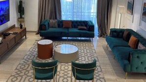 Un salon moderne avec un canapé turquoise, une table basse et des fauteuils assortis.