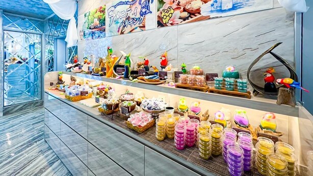 Une exposition de produits emballés aux couleurs vives, une pancarte « Bienvenue à Bali » et divers objets décoratifs.