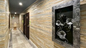 Un couloir aux murs ornés de motifs et agrémenté d’un panneau métallique décoratif aux motifs floraux.
