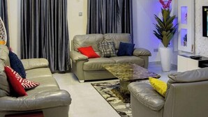 A modern living room with a sofa set, a coffee table, and a TV. - Safe Court Apartment (Lekki)