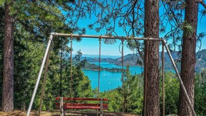 A swing set in a forested area with a lake and mountains in the background. - Beautiful Home Above Lake Shasta 30 nights minimum (Lakehead)