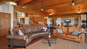 A spacious living area with a large L-shaped sectional sofa, a round coffee table, and a television mounted on the wall. - Beautiful Home Above Lake Shasta 30 nights minimum (Lakehead)