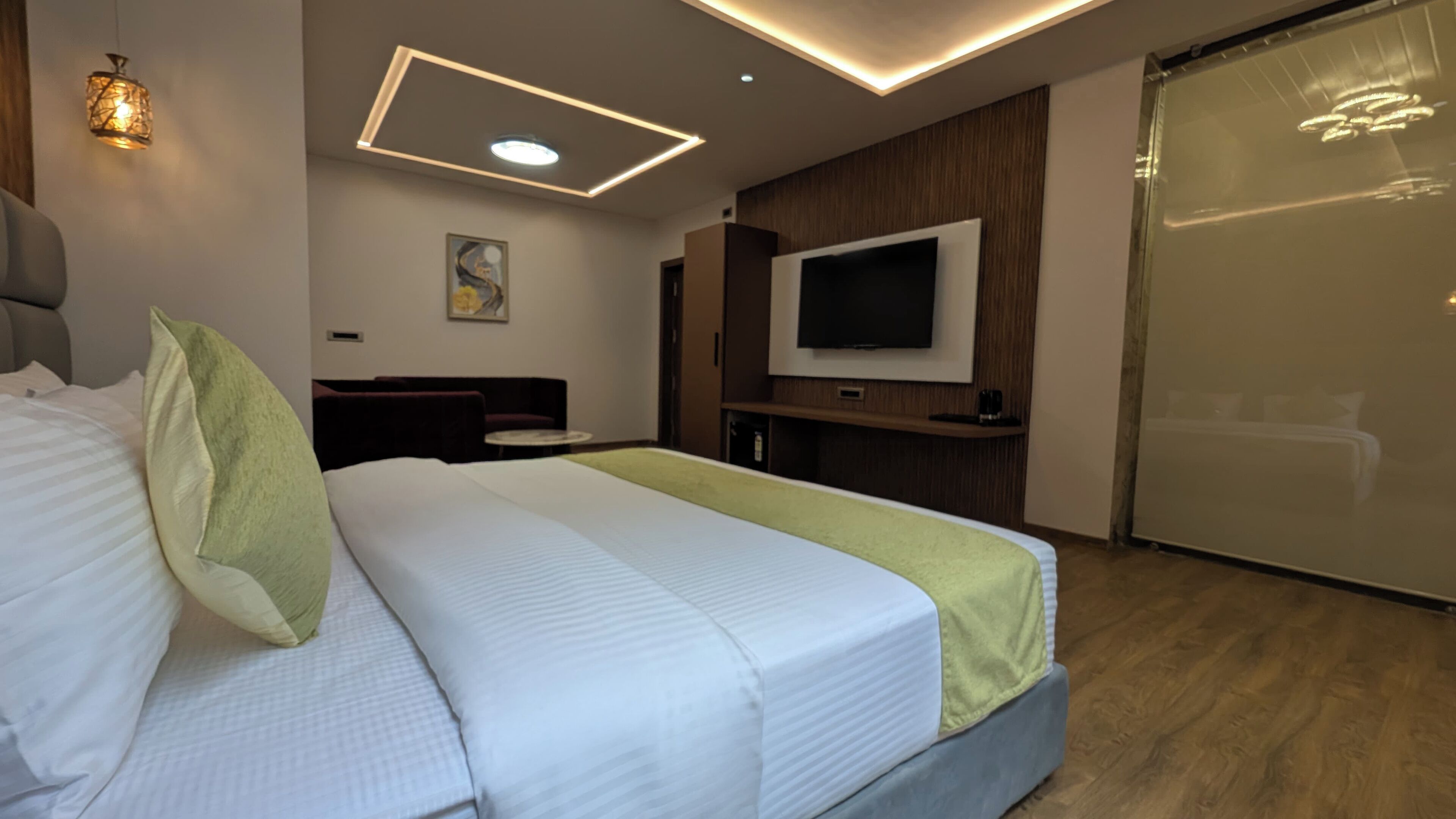Ein Hotelzimmer mit Bett, Fernseher, Schreibtisch und einer Schiebetür.