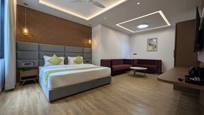Ein modernes Hotelzimmer mit einem großen Bett, einer Couch, einem kleinen runden Tisch und einem Fernseher.