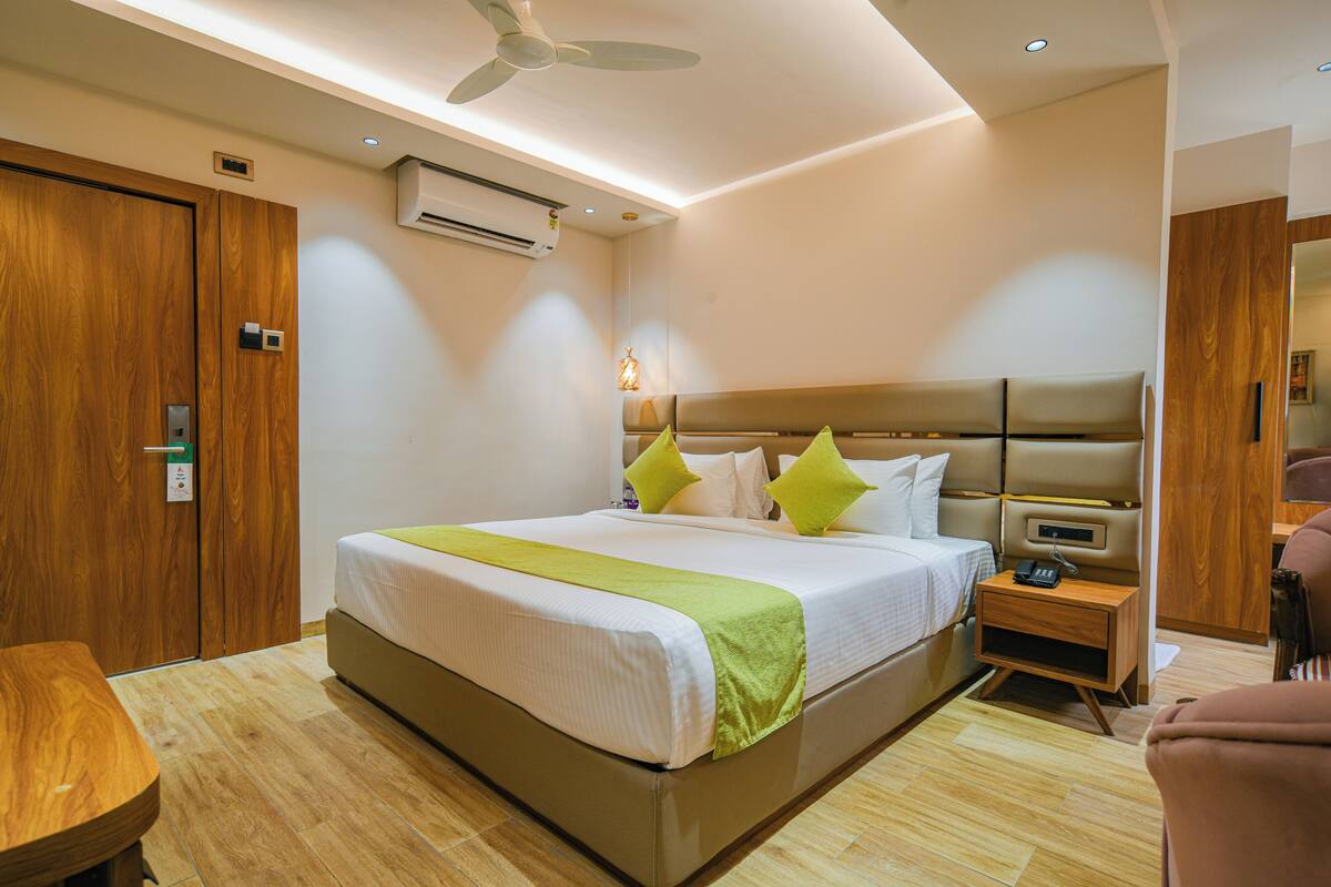 A modern hotel room with a large bed, bedside table, and a ceiling fan.