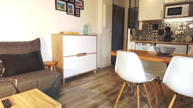 A compact living space with a sofa, a dining table with two chairs, a kitchenette with a microwave, and a refrigerator. - Charming t2 with loggia, beautiful sea view + parking lot (Saint Pierre La Mer)