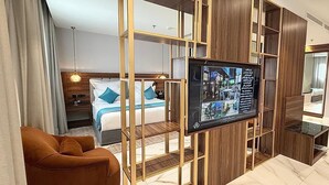 Et hotelværelse med seng, fjernsyn, sofa og en træskillevæg.
