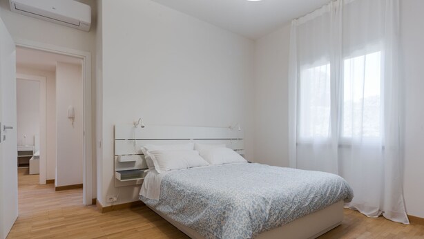Ein Schlafzimmer mit Bett, Nachttisch und einem Fenster mit Vorhängen.