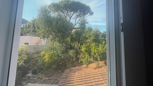 A window with a view of a tree and a building with a tiled roof. - Detached house in quiet neighborhood, hillside views, 10-minute walk to beach. (Cavalaire-sur-Mer)