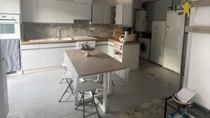 A compact kitchen with white cabinets, a central island, and a dining table with chairs. - Detached house in quiet neighborhood, hillside views, 10-minute walk to beach. (Cavalaire-sur-Mer)