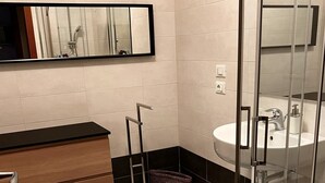 Un baño moderno con inodoro, lavamanos, espejo y ducha.