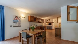 A modern kitchen with wooden cabinets, a dining area with a table and chairs, and a built-in oven.