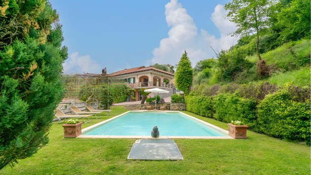 A swimming pool surrounded by lush greenery, with a house in the background.
