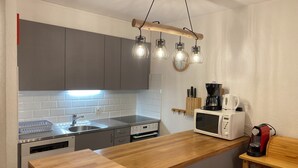 A modern kitchen with grey cabinets, a wooden countertop, a built-in dishwasher, a microwave, and a coffee maker.