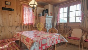 A cozy room with a wooden interior, a dining table with a checkered tablecloth, wicker chairs, and a fireplace. - A charming chalet with a parking space, rustic yet practical, spread over two floors, with a magnifi (St-Luc)