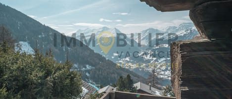 Vista sulle montagne con ringhiera in legno e una baita.