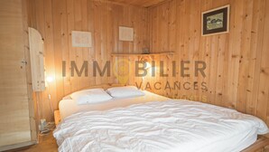 A wooden-paneled room with a bed, a shelf with a lamp, and a framed picture on the wall. - A charming chalet with a parking space, rustic yet practical, spread over two floors, with a magnifi (St-Luc)