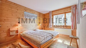 Une pièce en bois avec un lit, une fenêtre et une lampe fixée au mur.