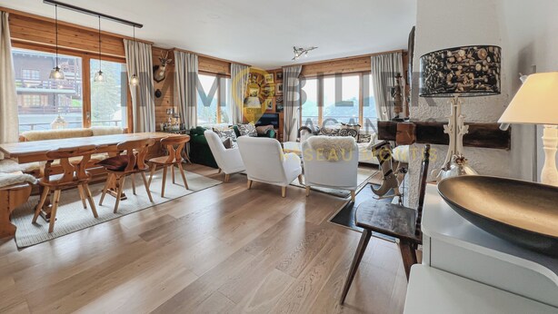 A spacious living room with a wooden dining table, comfortable seating, and large windows offering a view of the outside. - Situé à l'entrée du village, à proximité immédiate du bus navette et des commerces, ce lumineux et s (St-Luc)