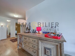 A modern kitchen with a wooden cabinet, a red tray, and various kitchen items on the counter. - Joli appartement de 4 pièces entièrement rénové, dans un immeuble à l'entrée du village, à proximité (St-Luc)