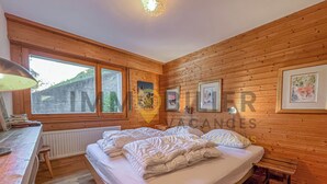 A wooden-paneled room with a bed, a desk, and a window.