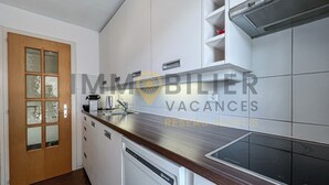 A modern kitchen with white cabinets, a wooden countertop, and a dishwasher.